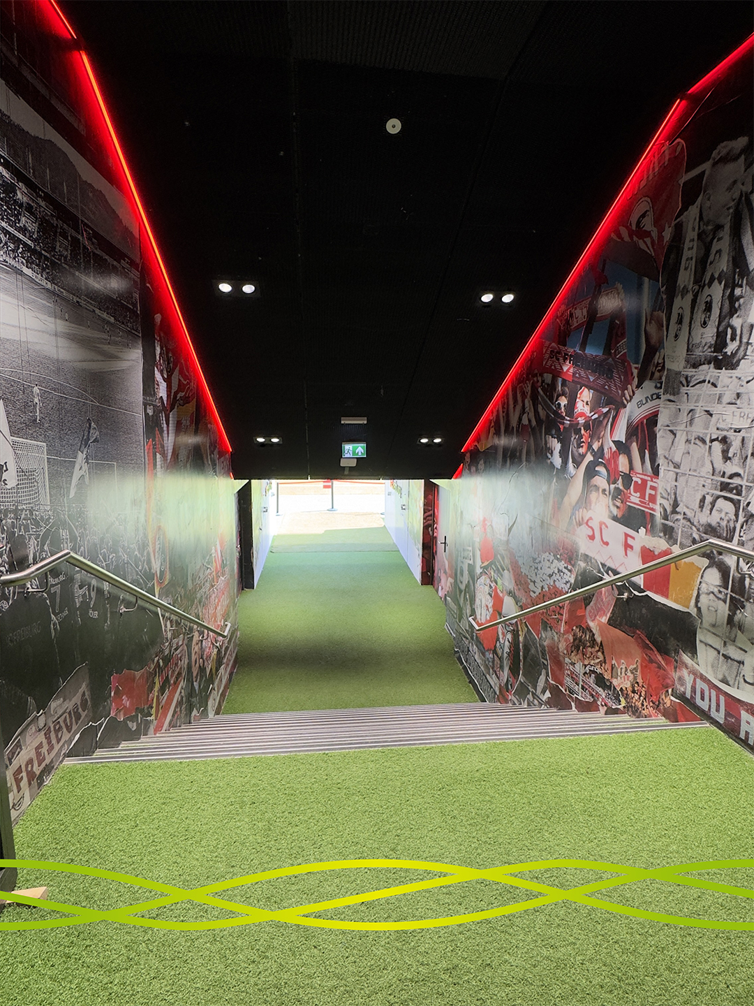 Blick durch den beleuchteten Spielertunnel des Europa-Park Stadions in Freiburg in Richtung Spielfeld während der Stadionführung beim Azubiausflug von Badenelektra.