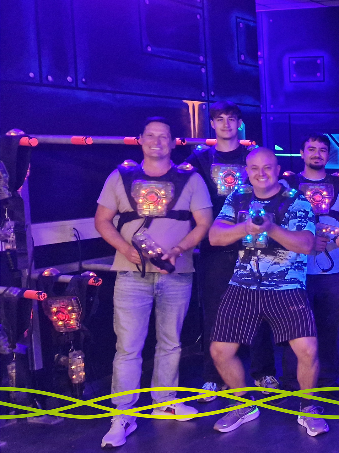 Teilnehmende des Badenelektra-Azubiausflugs mit Lasertag-Ausrüstung in der beleuchteten Arena der LASERZONE in Denzlingen.